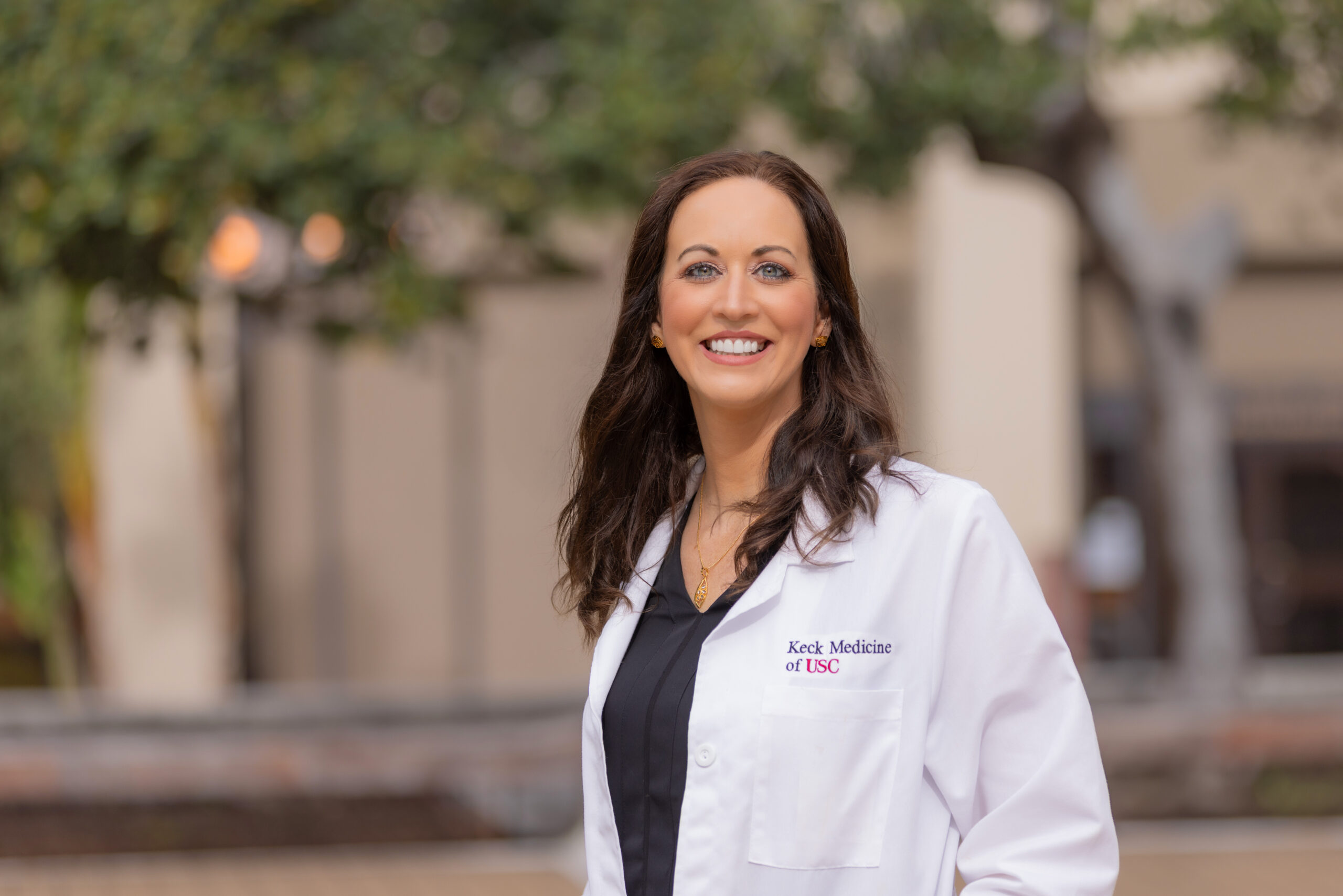Dr. Amanda Woodworth stands outside in a white coat and smiles.